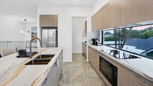 Una cocina moderna con una isla grande, electrodomésticos de acero inoxidable y vistas al exterior a través de un ventanal.