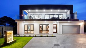 Una casa moderna de dos pisos con un amplio garaje, un balcón e ingreso bien iluminado.