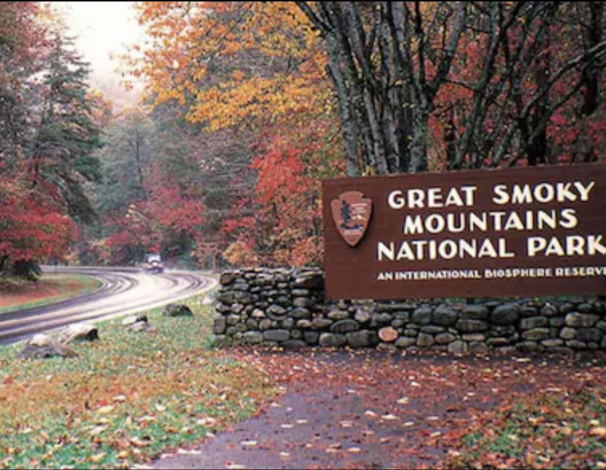 Een bordje voor Great Smoky Mountains National Park, met een stenen muur en herfstkleurige bladeren.