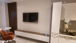 A modern kitchen with a built-in oven, a sink, and a flat-screen TV mounted on the wall. - Chic Studio in The Signature, Accra (Accra)