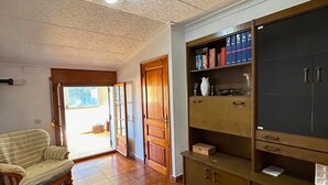 A living room with a sofa, a wooden cabinet with books, and a door leading outside.