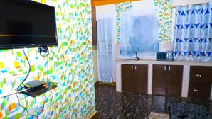 Une cuisine avec un téléviseur fixé au mur, un four à micro-ondes posé sur le plan de travail et des placards.