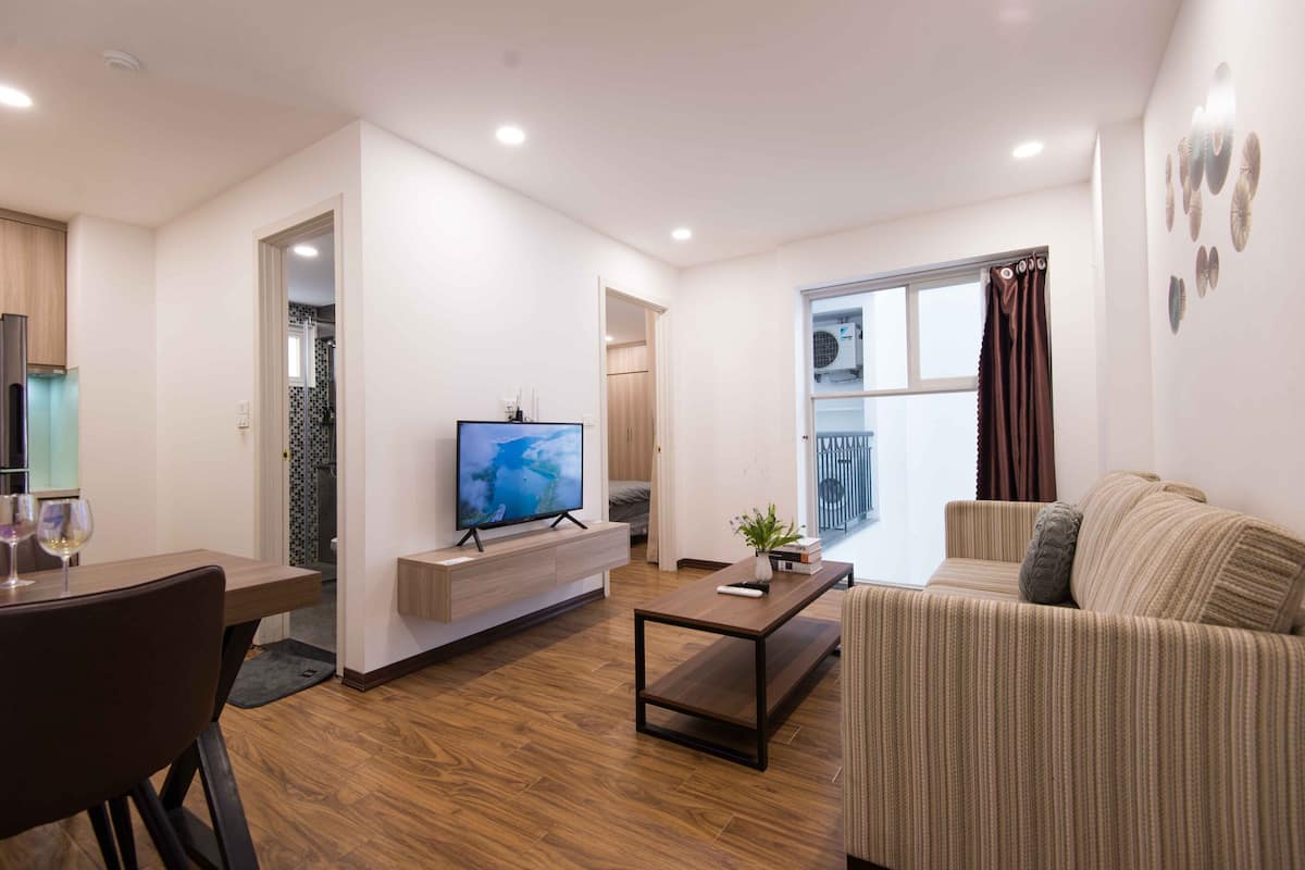 Ein modernes Wohnzimmer mit Fernseher, Sofa, Couchtisch und Essbereich.