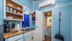 Cocina pequeña con armarios blancos, encimera de madera y pared azul.