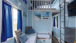 Una habitación con literas, un escritorio pequeño y una televisión.