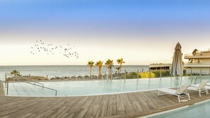 A poolside area with lounge chairs and umbrellas, overlooking the ocean.
