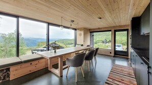 A modern kitchen with a wooden ceiling, large windows, and a view of the countryside.