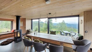 A modern kitchen with a large island, grey chairs, and a view of the countryside.