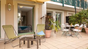 Un espace extérieur aménagé en terrasse, avec des sièges, une table et un pot de fleurs.