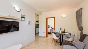 A modern living room with a flat-screen TV, a dining area with a table and chairs, and a cozy seating area with a sofa. - Nice apartment in Klek with WiFi (Klek)