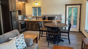 A modern kitchen with wooden cabinets, a dining area with a round table and chairs, and a staircase leading to a loft. - Cabin Retreat: Mountain Views, Starlink Wi-Fi, Stargazing, Hiking, Adventures! (Clinton)