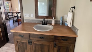 A bathroom with a wooden vanity, a large mirror, and three wall-mounted lights. - Cabin Retreat: Mountain Views, Starlink Wi-Fi, Stargazing, Hiking, Adventures! (Clinton)