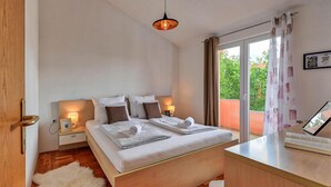 Habitación de hotel con una cama grande, lámparas de noche, vistas a zonas verdes por la ventana y un pequeño escritorio con una silla.
