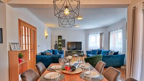 Una sala de estar moderna con comedor, que incluye un televisor, sofás y una mesa de comedor preparada para seis comensales.