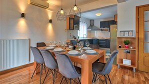 Comedor con mesa de madera dispuesta para cuatro, sillas grises tapizadas e iluminación colgante.
