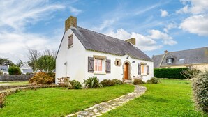Una casa bianca con un vialetto in pietra che conduce all'ingresso, circondata da un prato curato e un siepe.