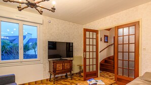 Un soggiorno con televisione, mobili in legno, un pavimento decorato e vista dalla finestra.