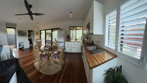 A spacious kitchen with a dining area, wooden flooring, and large windows. - The Bungalow - Luxurious & Calm | Beach & Bush (Valla Beach)