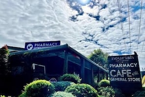 A pharmacy with a cafe and general store sign. - The Bungalow - Luxurious & Calm | Beach & Bush (Valla Beach)