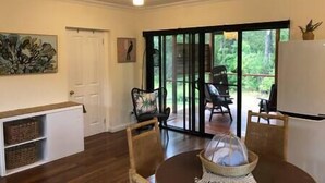 A dining area with a table, chairs, and a view through a glass door to an outdoor space. - The Bungalow - Luxurious & Calm | Beach & Bush (Valla Beach)