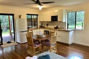 Una cocina con zona de comedor, refrigerador y ventana con vista a follaje.