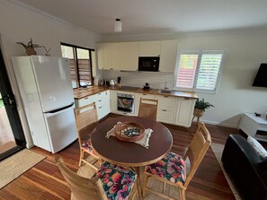 Une cuisine moderne avec des meubles blancs, une table à manger entourée de chaises à motifs floraux et un four encastré.