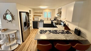A modern kitchen with a central island, stainless steel appliances, and a dining area with red chairs.