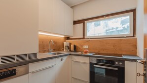 A modern kitchen with white cabinets, a built-in oven, and a window above the sink.