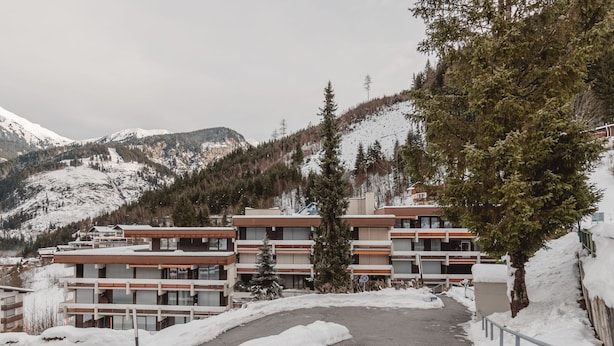 A modern multi-story hotel with a ski slope in the background.