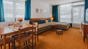 A cozy hotel room with a dining area, a sofa, and a desk.