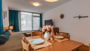 A modern living room with a wooden dining table, a sofa, and a TV.
