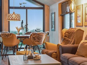 A cozy interior with a dining area, a sofa, and a view of the outdoors.