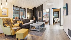 Een moderne woonkamer met een open haard, houten vloeren en een groot raam.