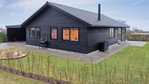 Een modern huis met twee verdiepingen, een donkere gevel, een schuin dak en een schoorsteen.
