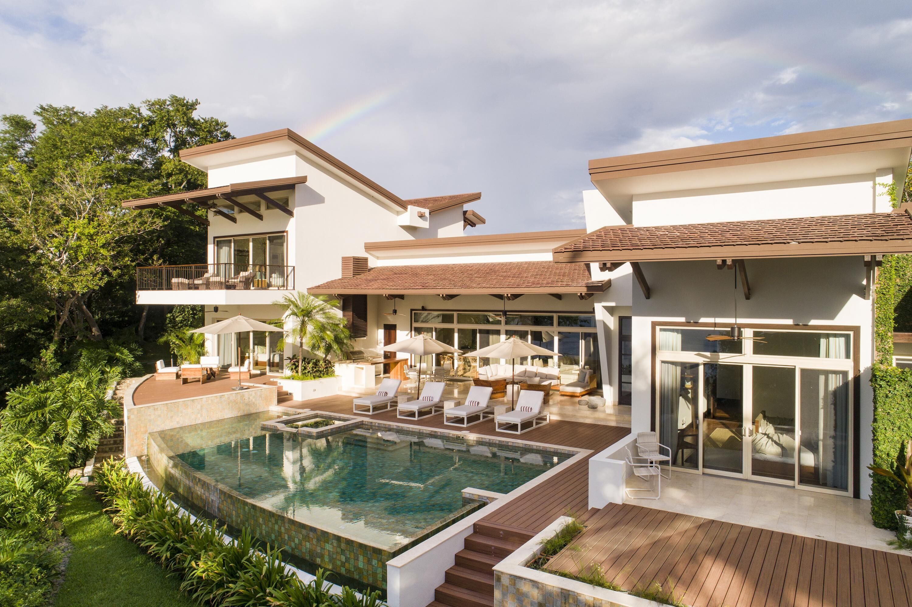 A modern house with a swimming pool, outdoor seating, and a large glass door.