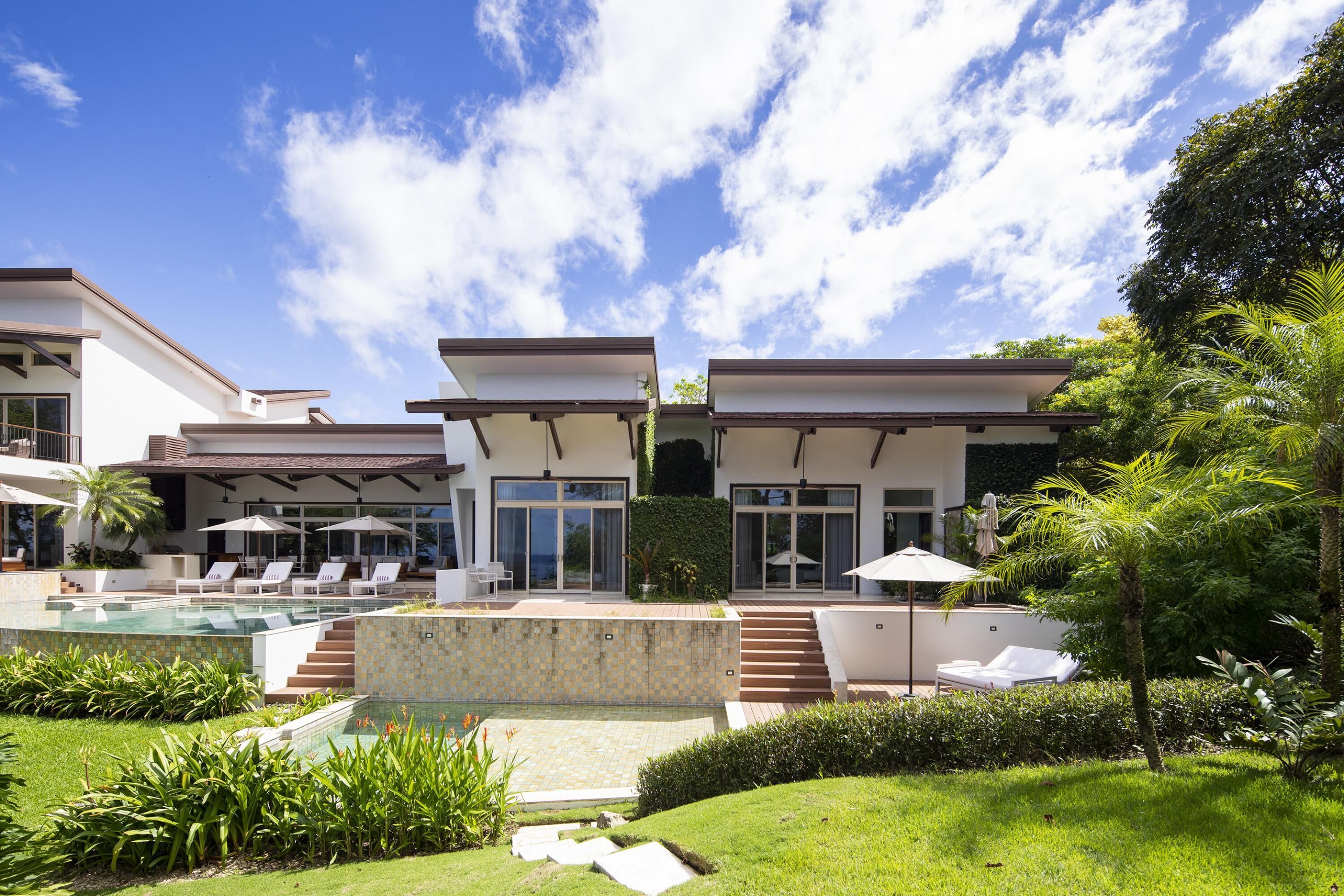 A modern resort with a swimming pool, outdoor seating, and lush greenery.
