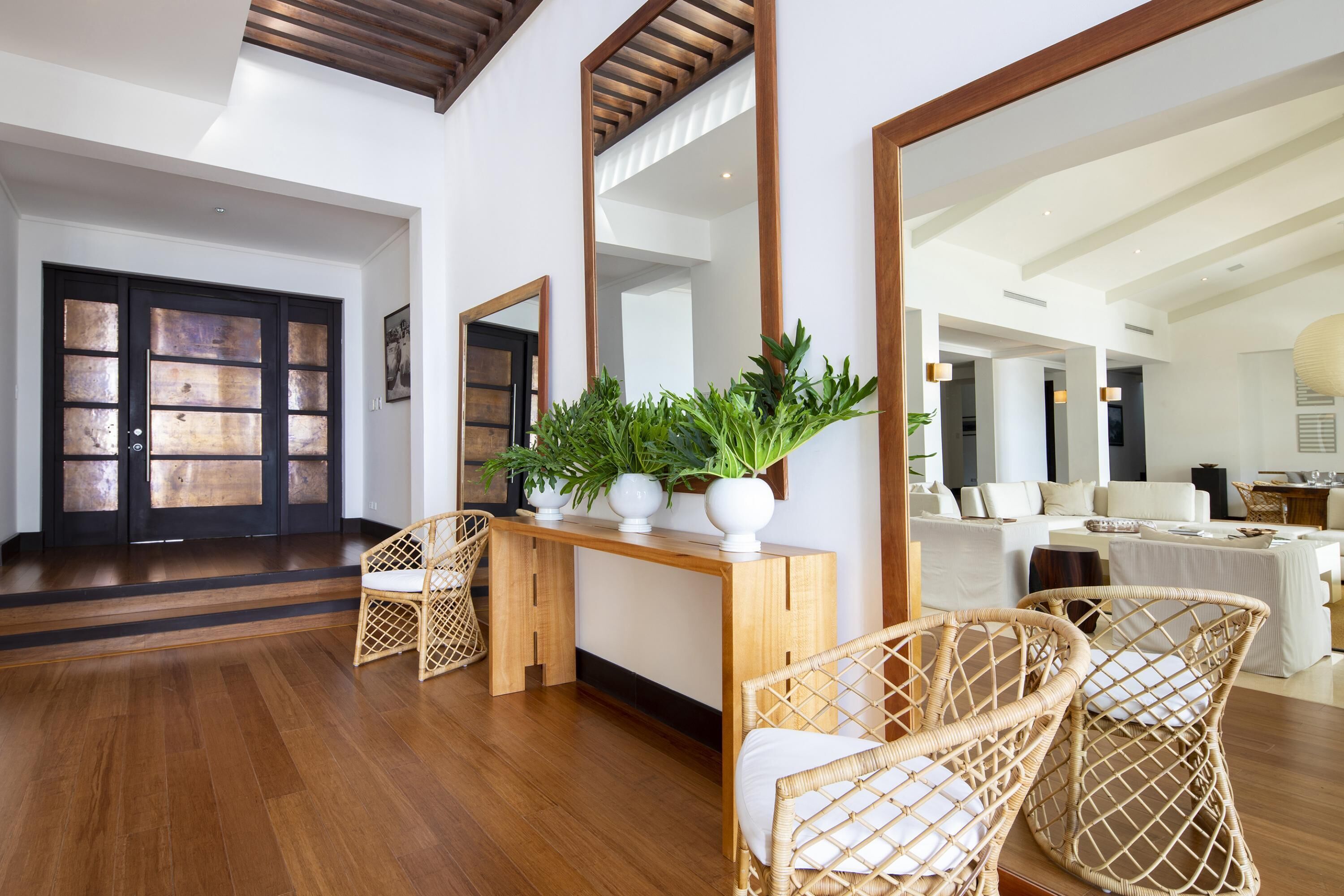 A spacious living area with a wooden console table, wicker chairs, and a large mirror.