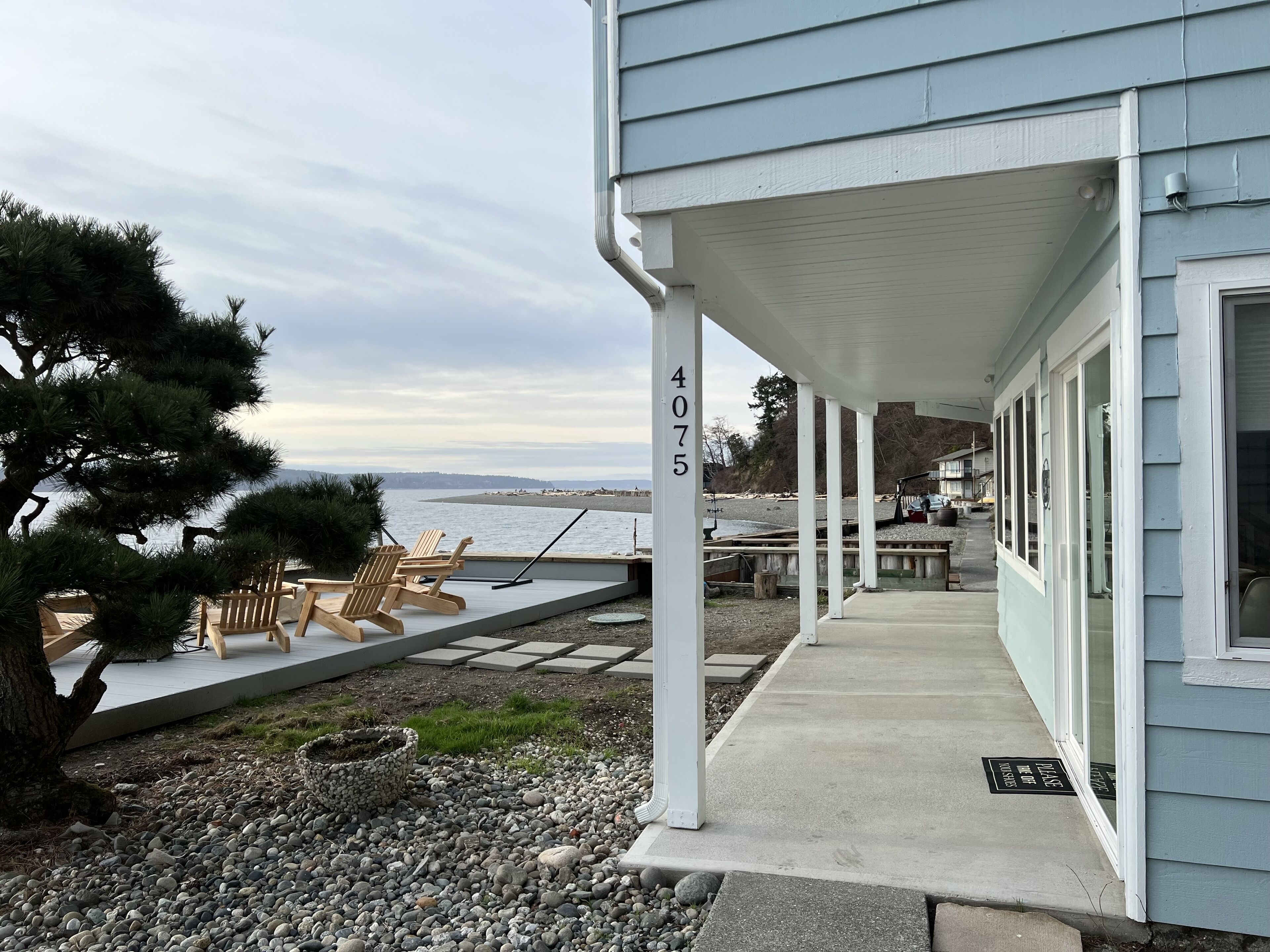 Ett hus vid kusten med en inglasad veranda, adresserat till 4075, med utsikt över en strand och havet.