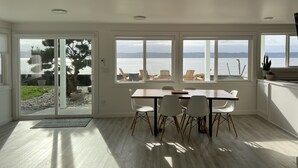 Un comedor moderno con vistas al agua, suelo de madera y un ventanal grande.