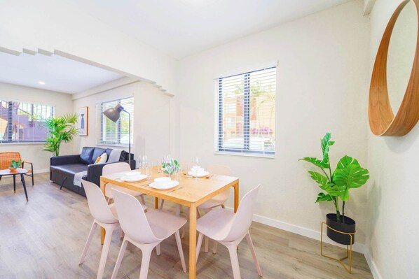 Un salon moderne avec une table à manger pour quatre personnes, un canapé et un grand miroir au mur.
