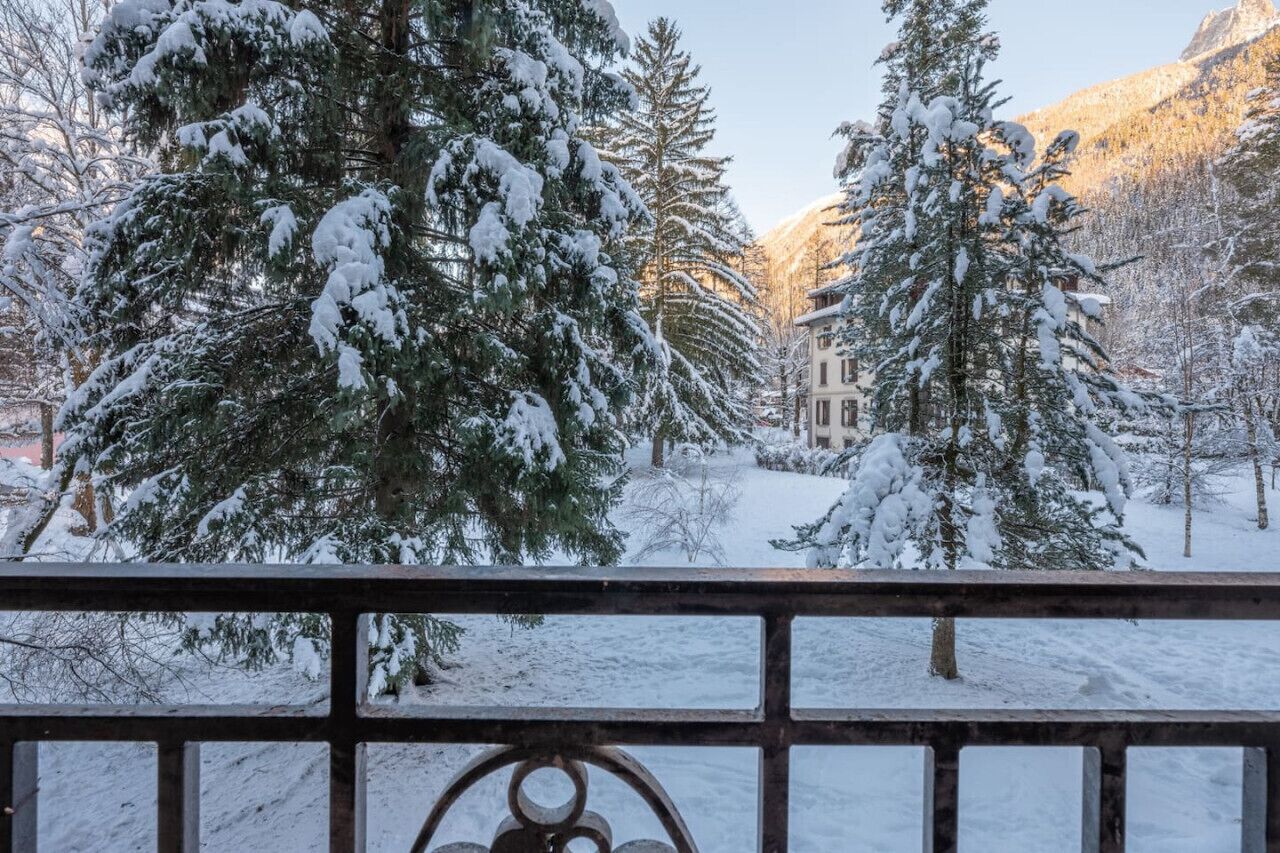 A snow-covered landscape with trees and a building in the background.