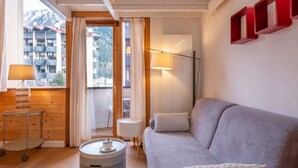 Una habitación acogedora con sofá, lámpara, una mesita y vistas a un edificio a través de una ventana.