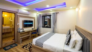 A hotel room with a bed, a desk, a TV, and a window with curtains. - Hotel Travel Inn (Kathmandu)