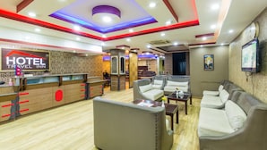 A hotel reception area with a reception desk, seating area with sofas, and a TV mounted on the wall. - Hotel Travel Inn (Kathmandu)