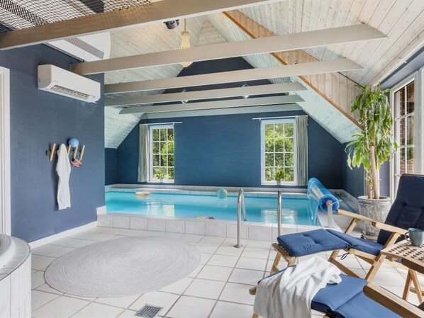 A pool area with a blue interior, a chair with a towel, and a potted plant.