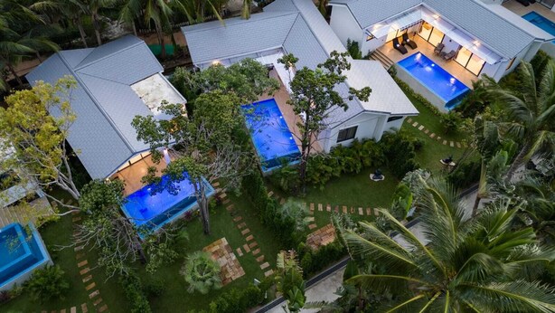 Un complexe hôtelier moderne doté de plusieurs piscines, d’une végétation luxuriante et d’un jardin bien entretenu.