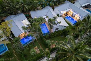 Un complexe hôtelier moderne doté de plusieurs piscines, d’une végétation luxuriante et d’un jardin bien entretenu.