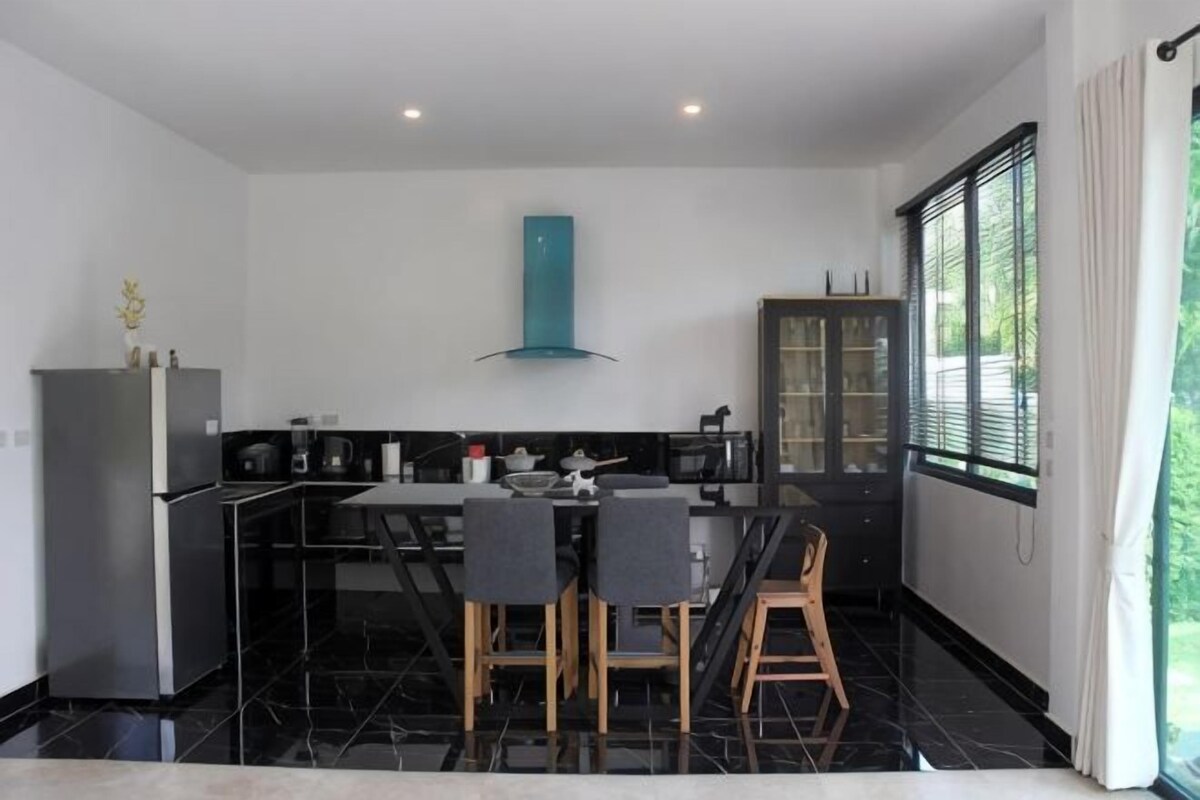 Una cocina moderna con una paleta de colores blanco y negro, una isla central con asientos y vistas al exterior.