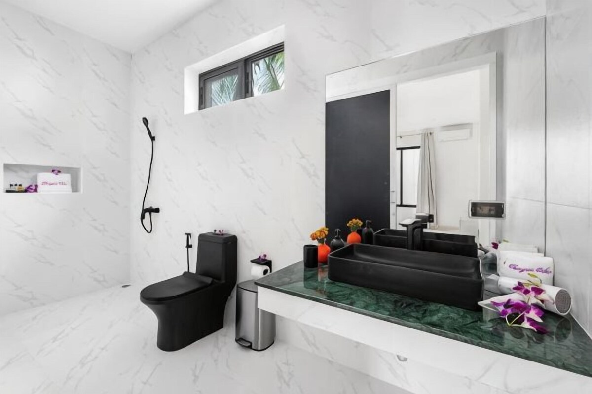 Ein modernes Badezimmer mit Toilette in Schwarz, einer Dusche, einer Marmorplatte und einem großen Spiegel.