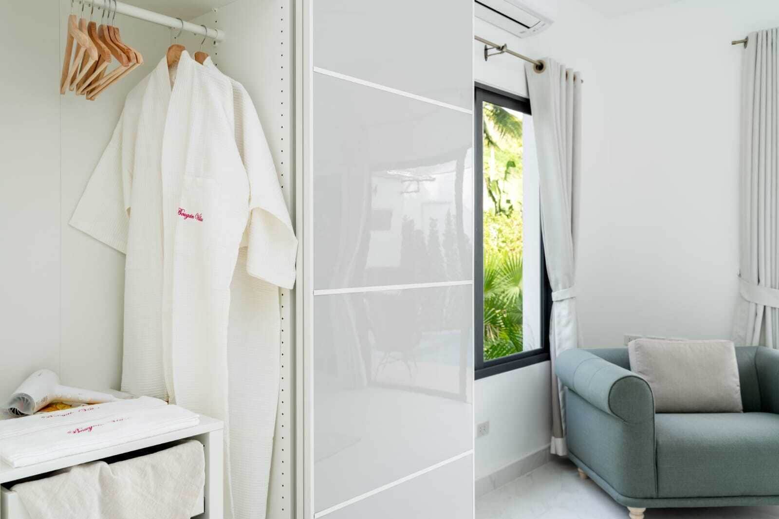 A bathroom with a white bathtub, a towel rack with wooden hangers, and a window with curtains.